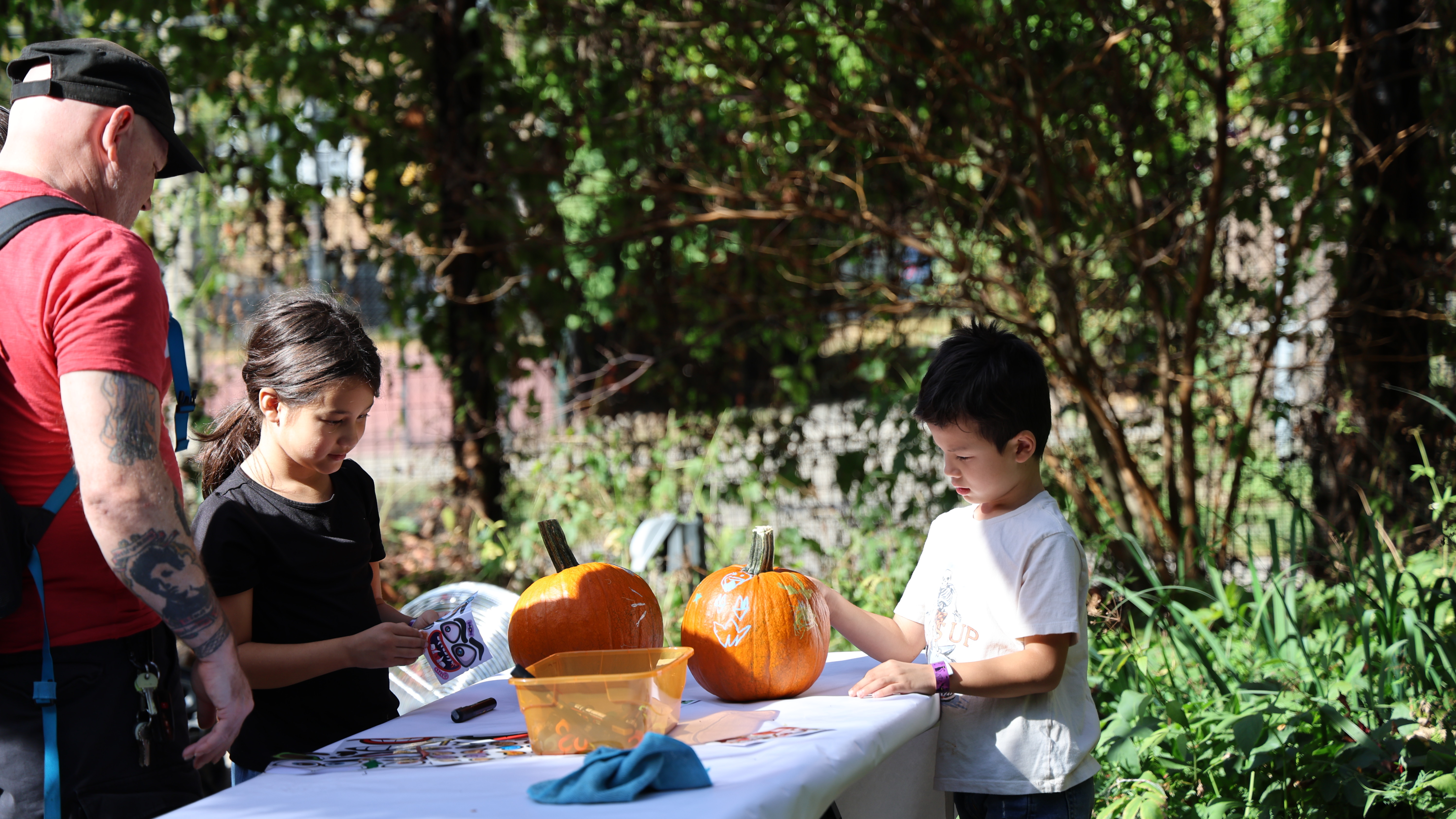 Two children decorating pumpkins outdoors.